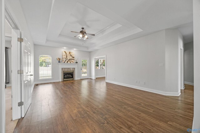 unfurnished living room with a tray ceiling, dark wood-type flooring, and ceiling fan