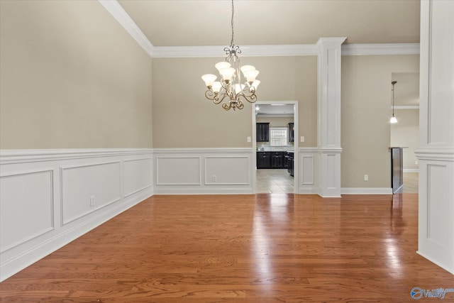 unfurnished dining area featuring hardwood / wood-style floors, an inviting chandelier, and crown molding