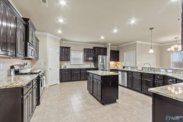 kitchen featuring appliances with stainless steel finishes, sink, pendant lighting, a notable chandelier, and a center island