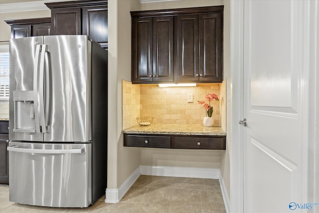 kitchen with light stone countertops, stainless steel fridge, tasteful backsplash, dark brown cabinetry, and light tile patterned flooring