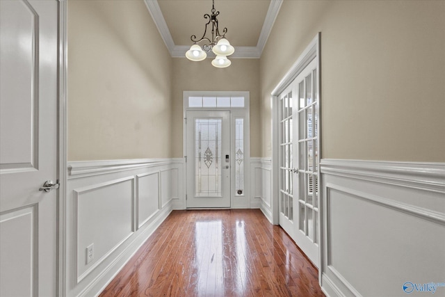 entryway with a chandelier, french doors, hardwood / wood-style flooring, and ornamental molding