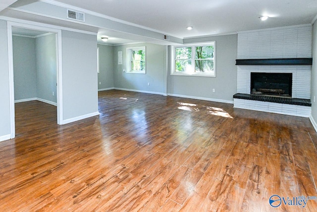 unfurnished living room with wood-type flooring, a fireplace, and crown molding