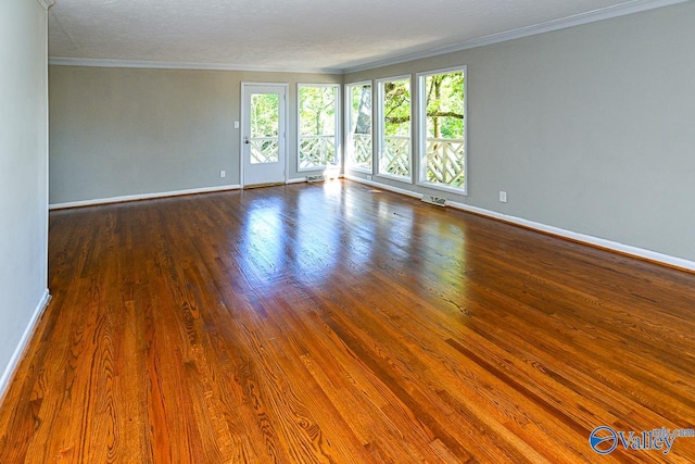 spare room with a textured ceiling, crown molding, and dark hardwood / wood-style flooring