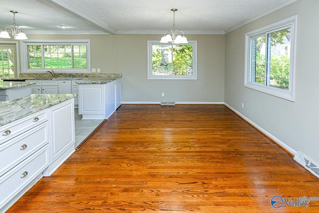 interior space featuring dark wood-type flooring, a wealth of natural light, white cabinetry, and an inviting chandelier