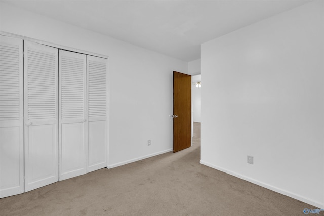 unfurnished bedroom with light colored carpet and a closet