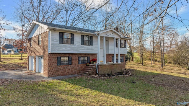 raised ranch featuring a garage and a front lawn