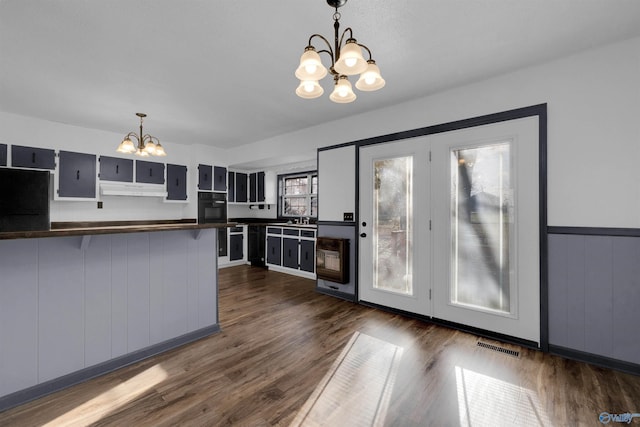 kitchen featuring refrigerator, black oven, decorative light fixtures, and an inviting chandelier