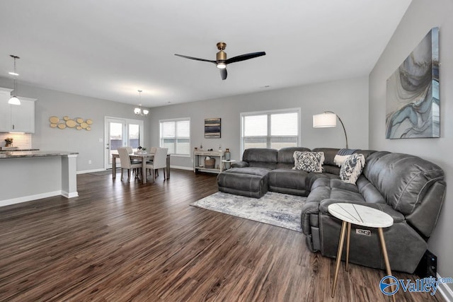 living room featuring ceiling fan with notable chandelier and dark hardwood / wood-style flooring