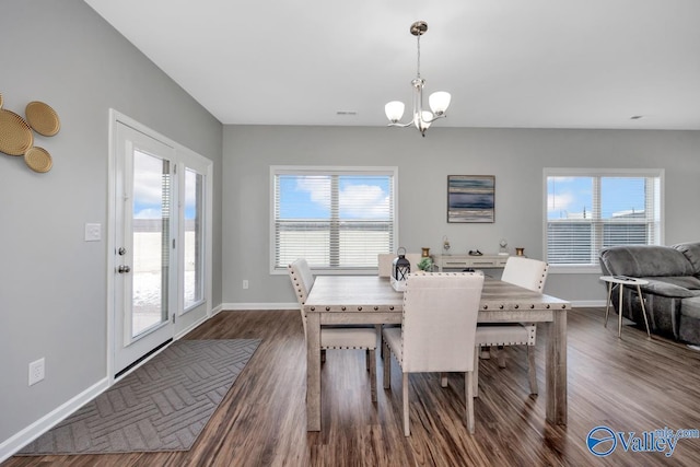 dining area with a healthy amount of sunlight, dark wood-type flooring, and a notable chandelier