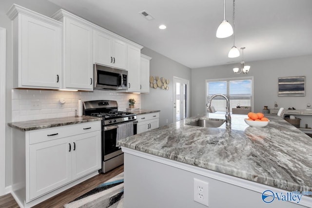 kitchen with sink, decorative light fixtures, white cabinetry, an island with sink, and appliances with stainless steel finishes