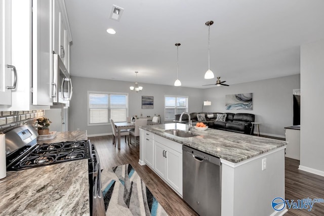 kitchen with light stone countertops, a kitchen island with sink, white cabinetry, appliances with stainless steel finishes, and sink