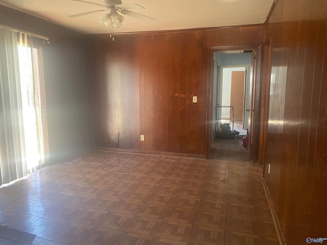 spare room featuring a ceiling fan, wooden walls, and baseboards