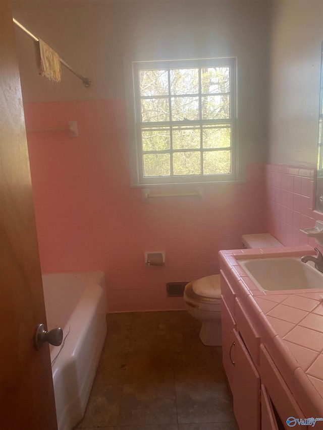 bathroom featuring tile patterned flooring, toilet, a washtub, vanity, and a shower