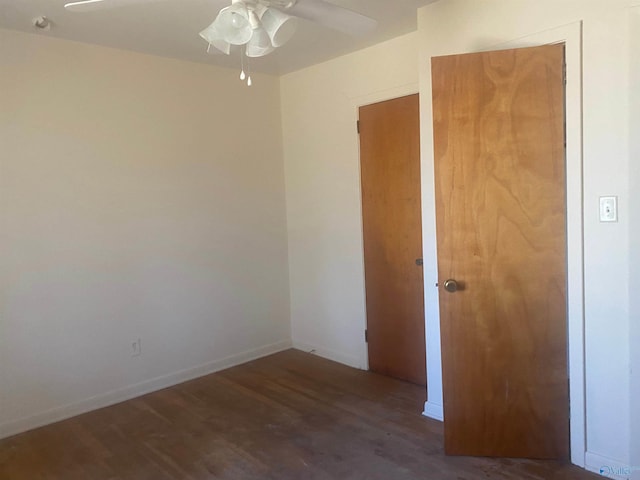 spare room with wood finished floors, a ceiling fan, and baseboards