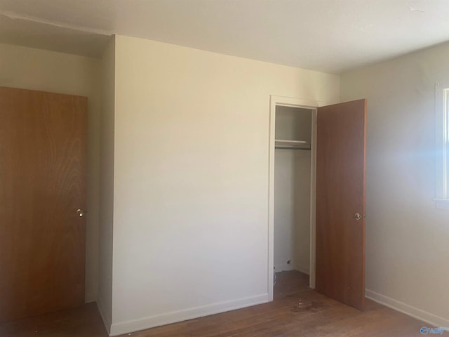 unfurnished bedroom featuring baseboards, a closet, and wood finished floors