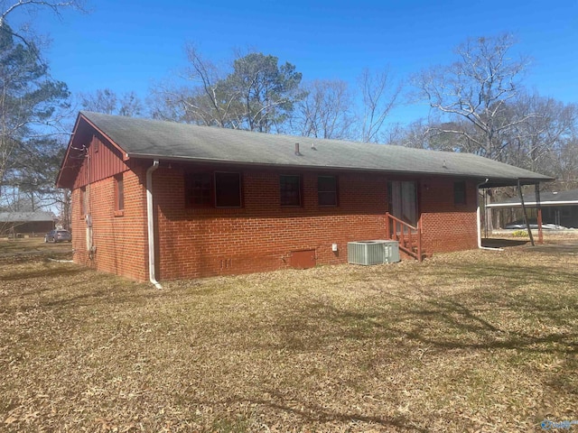 back of house with a yard, central AC unit, and brick siding