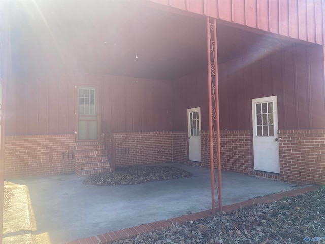 exterior space featuring entry steps, board and batten siding, and brick siding