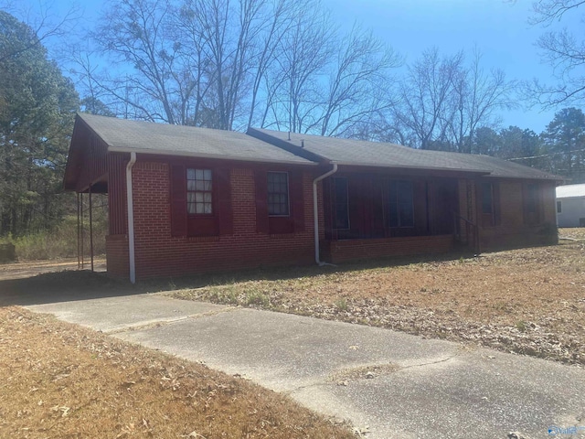 view of front of property featuring driveway, brick siding, and a porch