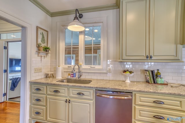 kitchen featuring light stone countertops, sink, hanging light fixtures, stainless steel dishwasher, and cream cabinetry