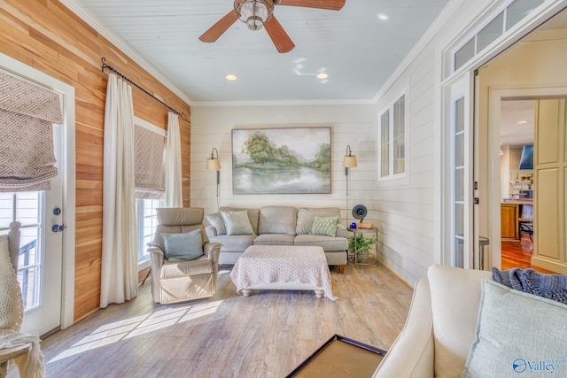 living room with plenty of natural light, ornamental molding, light hardwood / wood-style floors, and wood walls