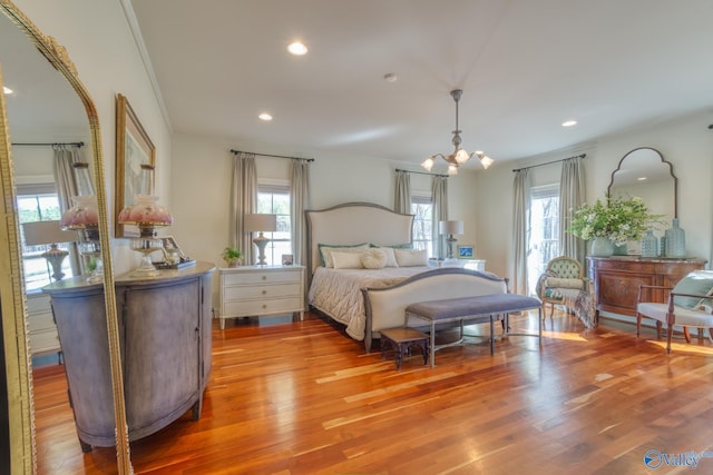 bedroom featuring multiple windows, hardwood / wood-style floors, ornamental molding, and an inviting chandelier