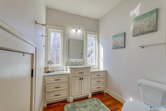 bathroom with toilet, vanity, and hardwood / wood-style floors