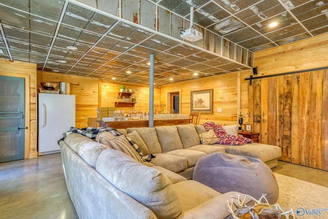 living room featuring wooden walls, a barn door, and concrete flooring