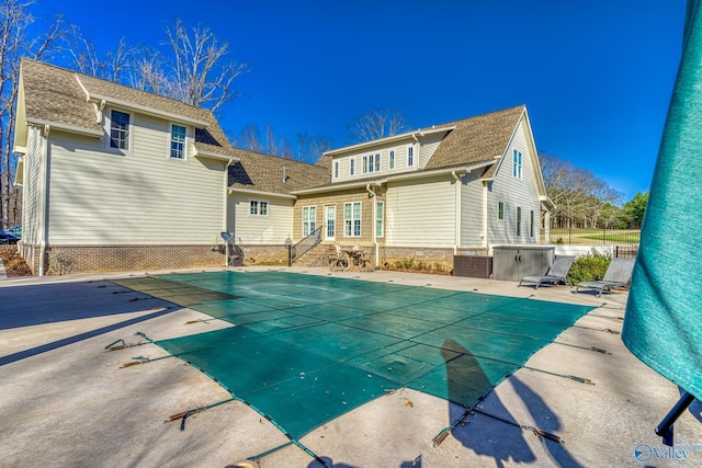 rear view of house featuring a covered pool and a patio area