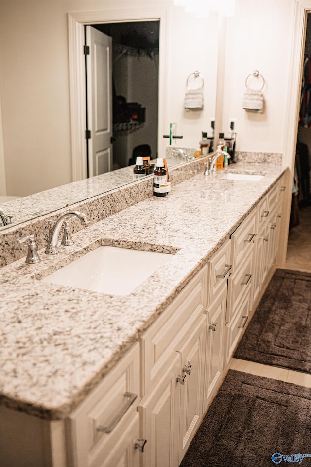 full bathroom with a sink, double vanity, and tile patterned flooring