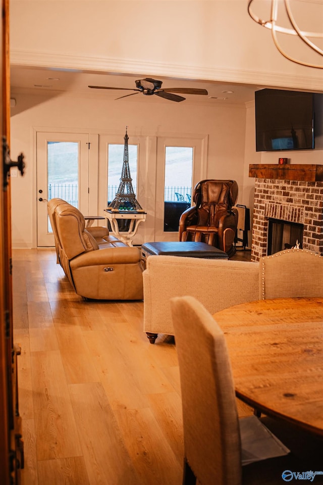 interior space featuring light wood finished floors, a brick fireplace, and a ceiling fan