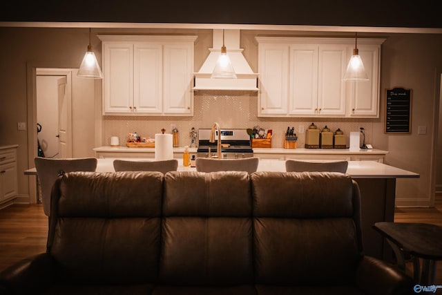 kitchen with wood finished floors, light countertops, stainless steel range with electric stovetop, pendant lighting, and white cabinetry