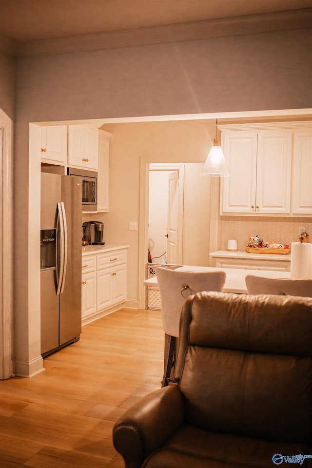 kitchen with stainless steel appliances, light wood-style flooring, light countertops, and white cabinetry