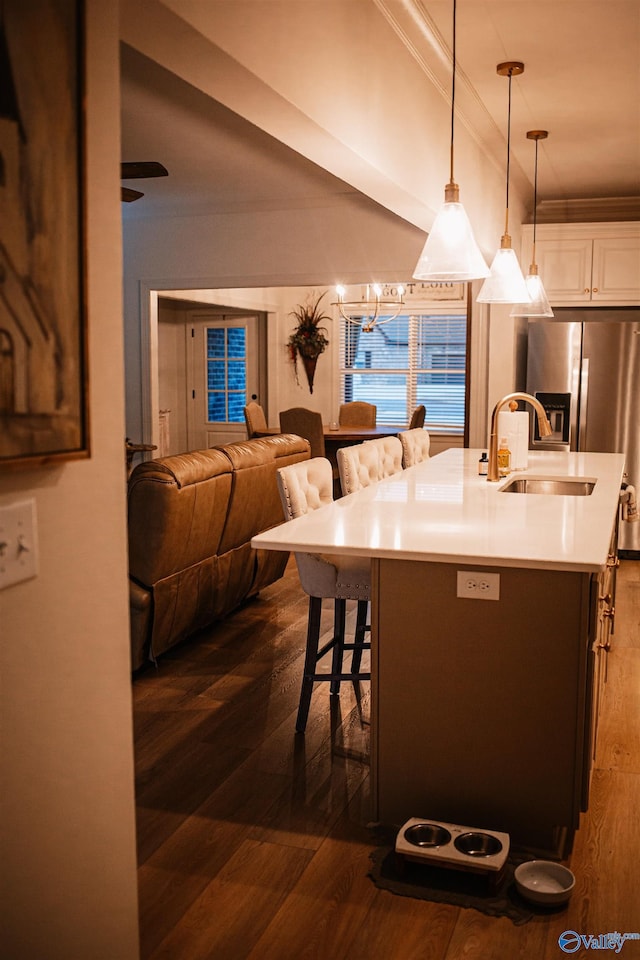 kitchen featuring crown molding, dark wood finished floors, open floor plan, a breakfast bar area, and hanging light fixtures
