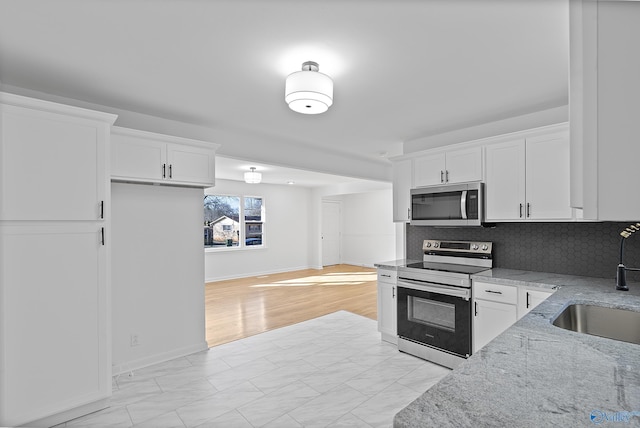 kitchen with white cabinets, stainless steel appliances, light stone counters, and tasteful backsplash