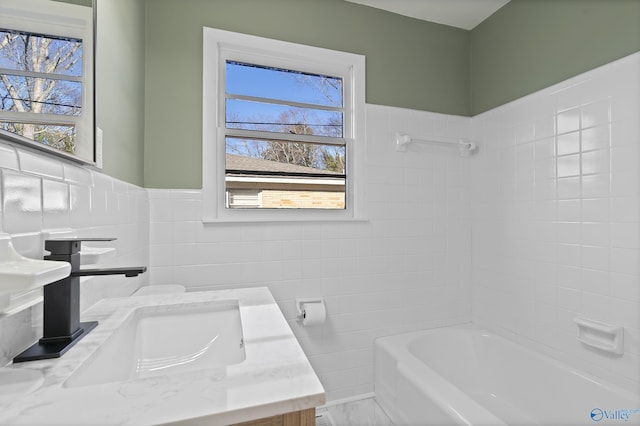 bathroom with vanity, a tub to relax in, and tile walls