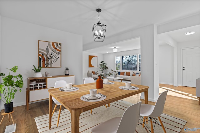 dining area featuring hardwood / wood-style flooring and an inviting chandelier