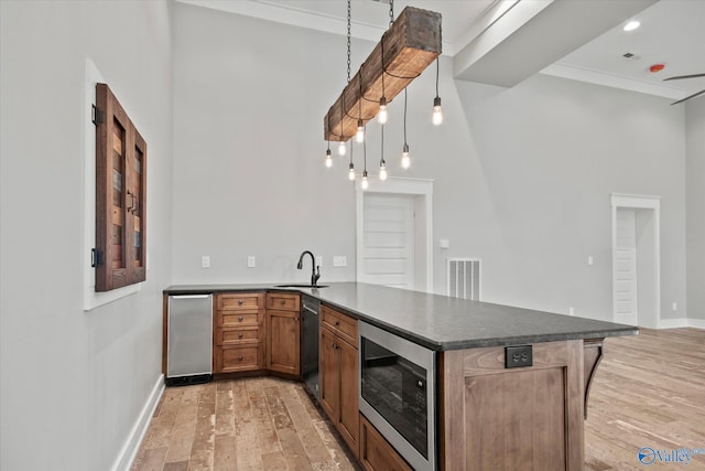 kitchen with pendant lighting, sink, appliances with stainless steel finishes, light hardwood / wood-style floors, and kitchen peninsula