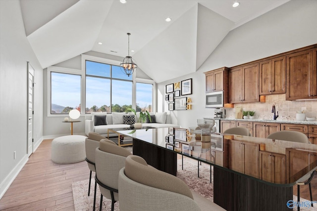 interior space with light hardwood / wood-style floors, vaulted ceiling, a notable chandelier, and sink