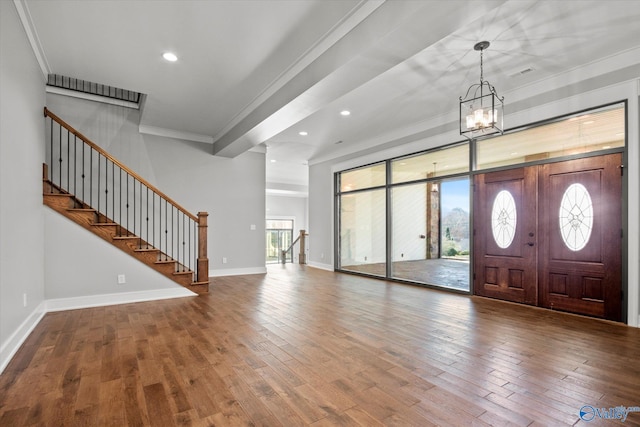 foyer entrance featuring wood-type flooring, an inviting chandelier, and ornamental molding