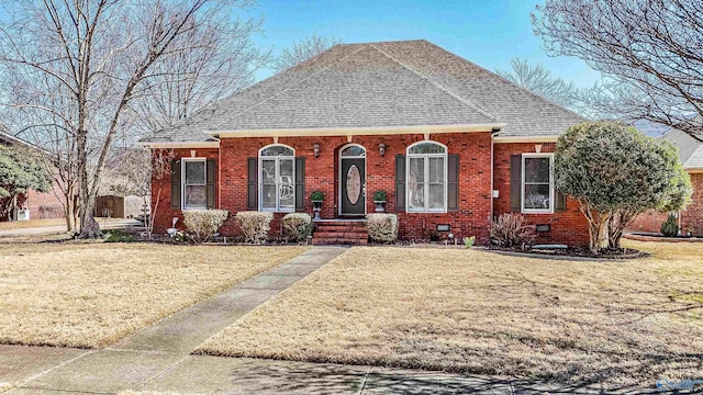 view of front facade featuring crawl space, brick siding, a front lawn, and a shingled roof