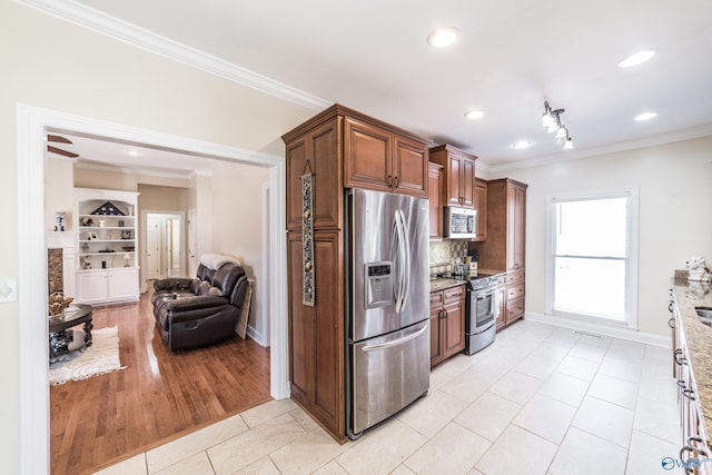 kitchen featuring open floor plan, ornamental molding, light tile patterned floors, light stone counters, and appliances with stainless steel finishes