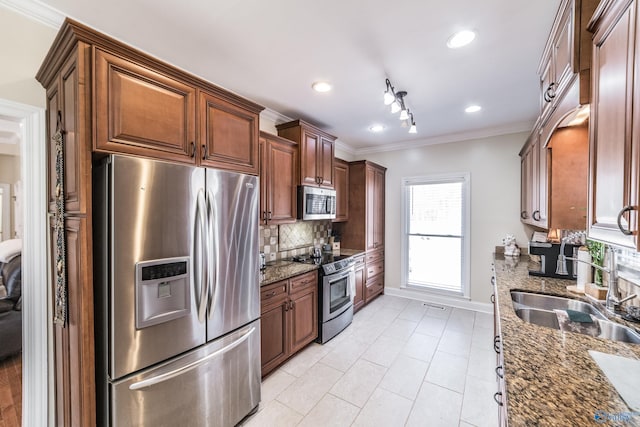 kitchen featuring dark stone countertops, a sink, ornamental molding, stainless steel appliances, and tasteful backsplash