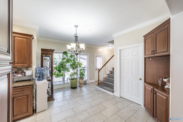 kitchen with an inviting chandelier, light tile patterned flooring, crown molding, baseboards, and hanging light fixtures