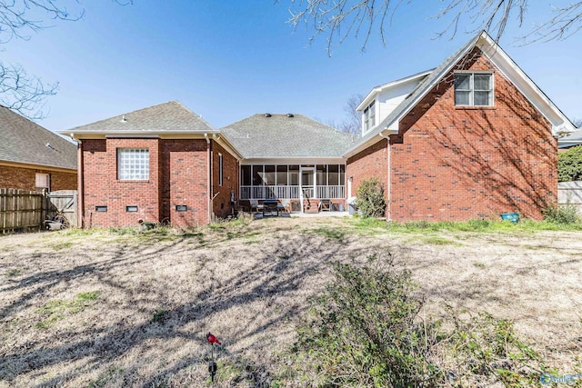 rear view of house with fence, roof with shingles, a sunroom, crawl space, and brick siding