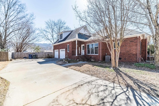 view of front facade featuring brick siding, fence, concrete driveway, cooling unit, and a garage