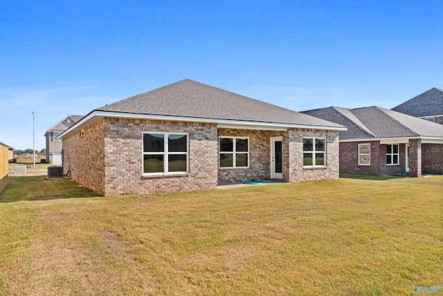 back of house featuring brick siding, a shingled roof, and a yard