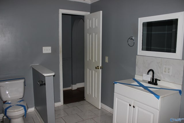 bathroom featuring vanity, toilet, and tasteful backsplash