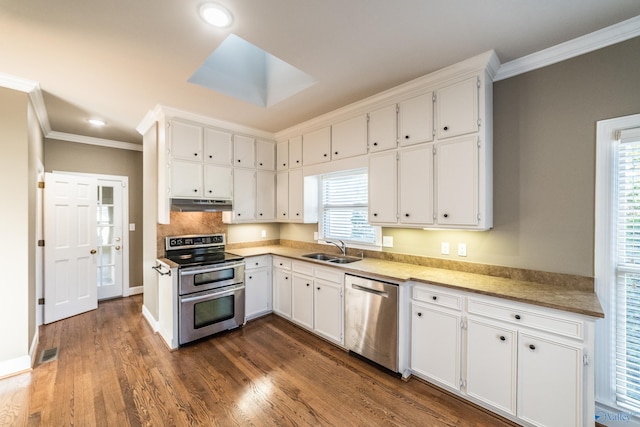 kitchen with a skylight, sink, white cabinets, and appliances with stainless steel finishes