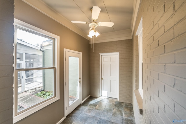 entryway with ceiling fan, brick wall, and lofted ceiling