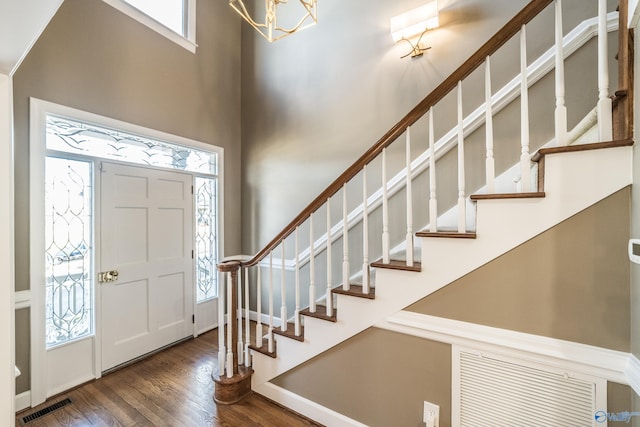 foyer entrance with dark hardwood / wood-style flooring and an inviting chandelier